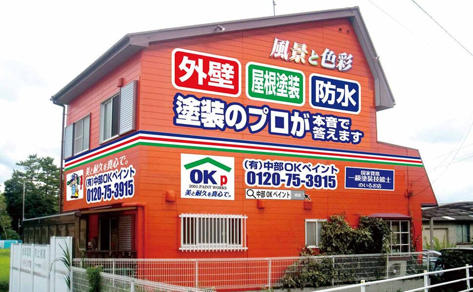 愛知県一宮市の塗装専門業者『中部OKペイント』の本社側面。オレンジ色の壁面に青や白で自社業務内容のペイントがされている。